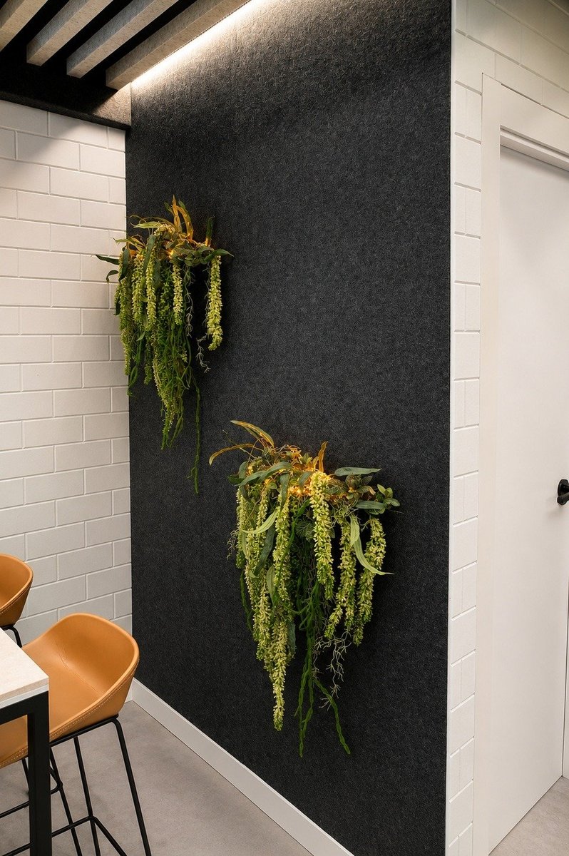 Comedor de oficina Viva Acoustic con pared acústica textil grafito y jardín vertical natural junto a azulejo metro blanco