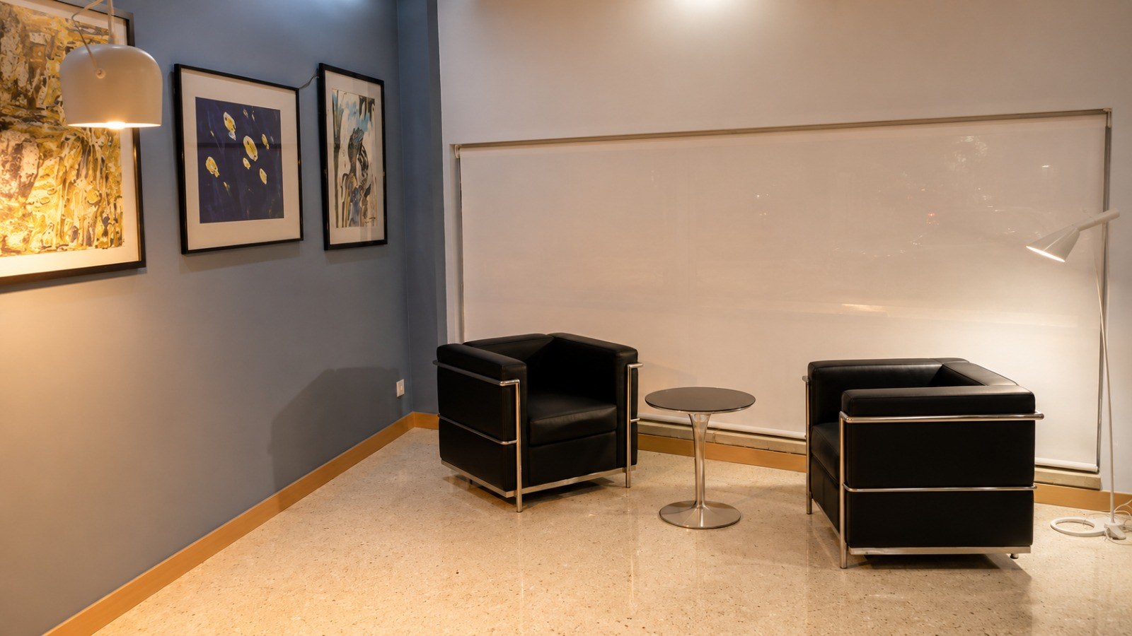 Recepción Hotelera — zona de descanso con butacas LC2, arte en pared y suelo de terrazo